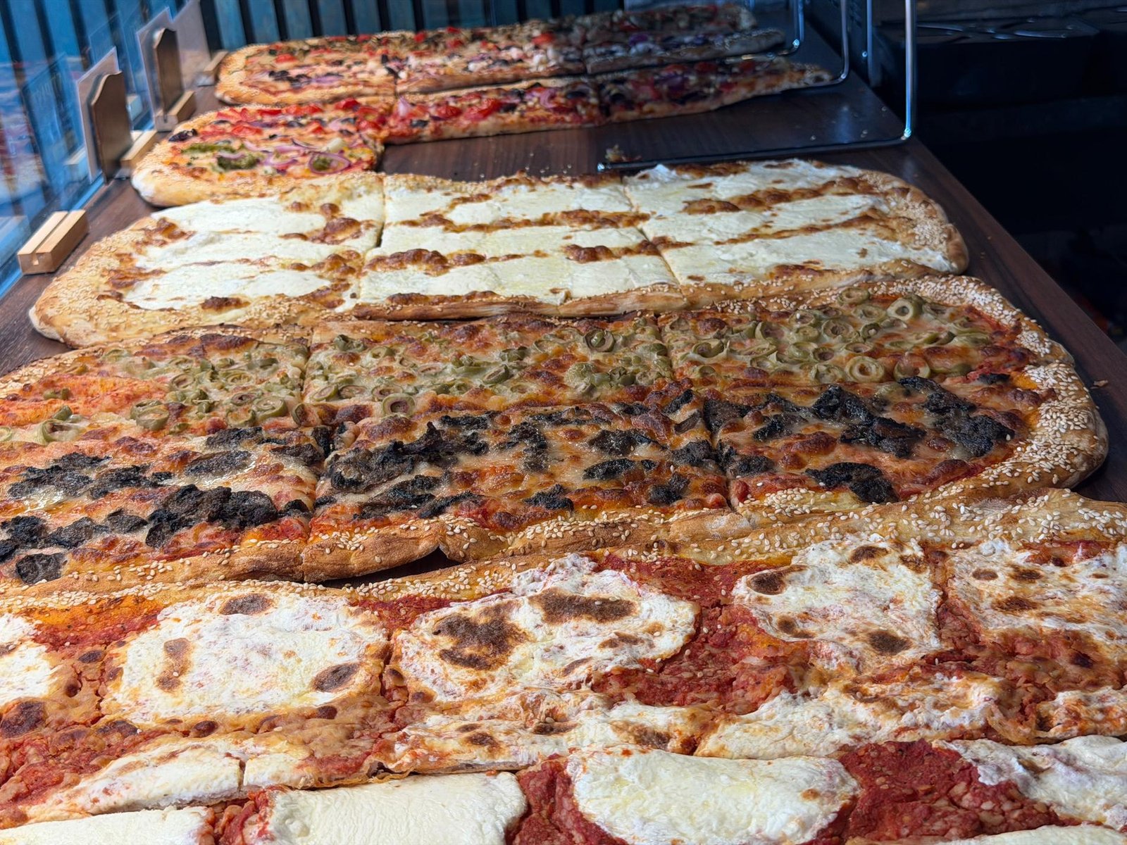 Trays of Roman-style pizza al taglio on the counter at La Mossa